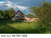 View of a traditional old outbuilding with a gate made of local limestone flagstone on a sunny summer day, Izborsk, Pskov region, Russia. Стоковое фото, фотограф Ula Ulachka / Фотобанк Лори