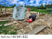Rigger uses roller bed system and winch to move concrete ring during installation of septic tank. Стоковое фото, фотограф Владимир Григорьев / Фотобанк Лори