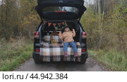 A little girl is sitting in the trunk of a car and wearing a witch hat for the Halloween holiday. The concept of children's Halloween. Стоковое видео, видеограф Терехова Марина / Фотобанк Лори