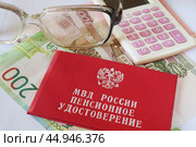 Пенсионное удостоверение МВД России и калькулятор лежат на денежных купюрах. Стоковое фото, фотограф Сергей Овчинников / Фотобанк Лори