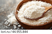 Wooden spoon scooping rice flour from bowl of grains. Стоковое AI-изображение, AI-художник Юрий Поздников / Фотобанк Лори