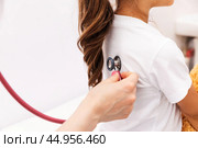 Close up female doctor holding stethoscope and doing lungs check up to little child. Smiling pediatrician examine her patient's respiration during routine checkup at modern pediatric clinic. Стоковое фото, фотограф Ирина Михайличенко / Фотобанк Лори