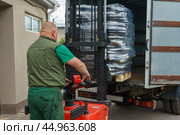Warehouse Worker Responsible for Operating Forklift to Efficiently Load and Unload Deliveries. Стоковое фото, фотограф Владислав Тригуб / Фотобанк Лори