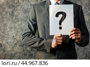 Businessman holding question mark sign seeking solution. Стоковое AI-изображение, AI-художник Иван Рябоконь / Фотобанк Лори