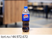 Belarus, Minsk - 18 july, 2024: A plastic bottle containing pepsi rests on a rustic wooden table. Редакционное фото, фотограф Аксенова Вера / Фотобанк Лори