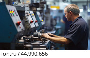 A technician operates machinery in a manufacturing facility during working hours, focusing on precision engineering tasks. Стоковое AI-изображение, AI-художник Сергей Толмачёв / Фотобанк Лори