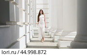 Young beautiful girl in a long white dress walks in the columned hall. Стоковое видео, видеограф Андрей Аркуша / Фотобанк Лори