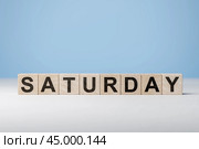 Word Saturday on wooden cubes. Weekday concept. Saturday inscription on wooden cubes on blue background. copy space. Стоковое фото, фотограф Павел Муравьев / Фотобанк Лори
