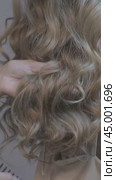 Vertical video of woman stylist combing long wavy blond female hair from back side. Стоковое видео, видеограф Сергей Пристяжнюк (Serg Zastavkin) / Фотобанк Лори