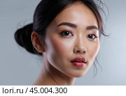 A close-up portrait of an Asian woman with a fresh, natural look, her expression soft and confident, showcasing her glowing skin and simple elegance. Стоковое AI-изображение, AI-художник Ольга Игнашина / Фотобанк Лори