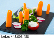 Vegetarian dish, carrots with greens, onion and tomatoe served at black plate. Стоковое фото, фотограф Яков Филимонов / Фотобанк Лори