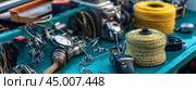 A close-up view of fishing tools and equipment on a blue workbench at a waterfront location during the late afternoon sun. Стоковое AI-изображение, AI-художник Сергей Толмачёв / Фотобанк Лори