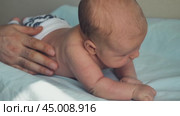 A newborn baby lying on its stomach and trying to hold its head. Close-up. A parent's hand is supporting the baby from the side so that he does not turn over. Стоковое видео, видеограф Воловодов Владимир / Фотобанк Лори