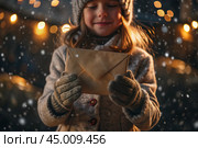 A little girl in winter clothes holding an envelope outside in snowy weather against the background of lights. A letter for Santa Claus. The winter atmosphere of a festive invitation. Стоковое AI-изображение, AI-художник Photojuli / Фотобанк Лори