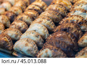 Rows of golden baked empanadas displayed on countertop of bakery. Стоковое фото, фотограф Яков Филимонов / Фотобанк Лори
