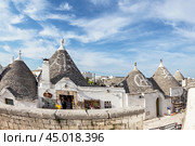 Alberobello, Puglia, Italy - June 26, 2019: Street in the village of Trulli with white houses with conical stone roofs. Редакционное фото, фотограф Лариса Гордеева / Фотобанк Лори