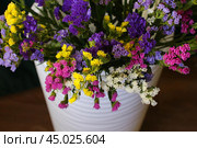 Bouquet of multicolored flowers in a vase (Limonium sinuatum, Statice sinuata) on a green background. Стоковое фото, фотограф Ирина Вершинская / Фотобанк Лори