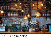 Blurred background of modern cafe interior with hanging edison light bulbs. Стоковое AI-изображение, AI-художник Иван Рябоконь / Фотобанк Лори