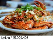 Delicious seafood dish of crab and prawns covered in garlic and spring onions. Стоковое AI-изображение, AI-художник Иван Рябоконь / Фотобанк Лори