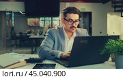 Business professional working intently on a laptop in a modern office environment during the daytime. Стоковое видео, видеограф Сергей Толмачёв / Фотобанк Лори