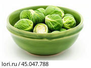 Green bowl overflowing with fresh raw brussel sprouts on white. Стоковое AI-изображение, AI-художник Иван Рябоконь / Фотобанк Лори