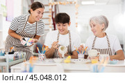 Group of cheerful people painting ceramic dishware in pottery class. Стоковое фото, фотограф Яков Филимонов / Фотобанк Лори