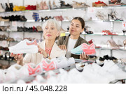 Elderly mom strongly recommends her doughter to pay attention to classic model of light sneakers. Стоковое фото, фотограф Яков Филимонов / Фотобанк Лори