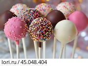 Colorful cake pops covered in sprinkles standing upright. Стоковое AI-изображение, AI-художник Иван Рябоконь / Фотобанк Лори