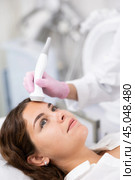 Faceless cosmetologist doing facial skin ultrasound cavitation for flawless woman face in beauty salon. Стоковое фото, фотограф Яков Филимонов / Фотобанк Лори