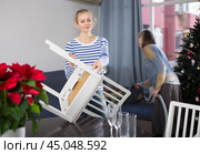 Young woman dusts chair while an elderly mother vacuums room before Christmas. Стоковое фото, фотограф Яков Филимонов / Фотобанк Лори