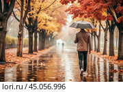 Rainy autumn weather. A man under an umbrella walks along an autumn alley in the park. Стоковое AI-изображение, AI-художник Photojuli / Фотобанк Лори