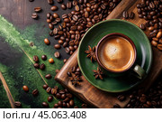 Cafes and restaurants. A mug of invigorating black coffee and coffee beans on a vintage green table. Стоковое AI-изображение, AI-художник Photojuli / Фотобанк Лори