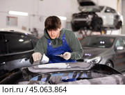 Young auto body technician applying filler to damaged car bumper in garage. Стоковое фото, фотограф Яков Филимонов / Фотобанк Лори