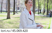 SMS. Young blonde woman reads messages on cellphone sitting on bench in park. Стоковое видео, видеограф Андрей Аркуша / Фотобанк Лори