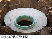 Construction of a septic tank. Large concrete rings embedded in the ground, from above an open sewer hatch, unprotected by a cover from falling. Стоковое фото, фотограф Коханова Наталья / Фотобанк Лори