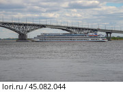 Круизный теплоход подходит к мосту через Волгу между городами Саратов и Энгельс (2024 год). Редакционное фото, фотограф Анна Карасева / Фотобанк Лори