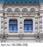 Close up view on a facade of white ancient building with decorative ornaments and two windows. Стоковое фото, фотограф Михаил Строгалев / Фотобанк Лори