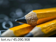 Three sharpened pencils laying on a textbook open to a blurred page. Стоковое AI-изображение, AI-художник Иван Рябоконь / Фотобанк Лори