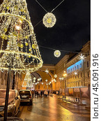 SAINT PETERSBURG, RUSSIA-December 25, 2023: People walking along Bolshaya Morskaya Street decorated with garlands and Christmas trees near arch of General Staff Building in X-Mas and New Year holidays. Редакционное фото, фотограф Виктория Катьянова / Фотобанк Лори