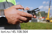 a surveyor on a construction site controls a quadcopter. Стоковое видео, видеограф Igor Skripachev / Фотобанк Лори