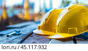 Yellow construction helmets and other tools  lying on wooden planks for labor day celebration. Стоковое AI-изображение, AI-художник Anastacia Gaikova / Фотобанк Лори