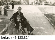 Мужчина с маленькой девочкой сидят на скамейке в парке. 1950-е годы. Стоковое фото, фотограф Retro / Фотобанк Лори