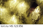 Transparent skeletons glowing yellow, close-up. Transform your space with a whimsical garland featuring glowing skeleton skulls and bones, perfect for Halloween festivities and ambiance. Horror theme. Стоковое видео, видеограф Юлия Петровская / Фотобанк Лори