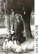 Женщина и маленькая девочка корvят кур на улице. 1970-е годы. Стоковое фото, фотограф Retro / Фотобанк Лори