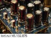 Electrolytic capacitors standing on a printed circuit board. Стоковое AI-изображение, AI-художник Иван Рябоконь / Фотобанк Лори