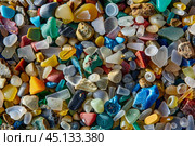 Colorful microplastics washed up forming background on the beach. Стоковое AI-изображение, AI-художник Иван Рябоконь / Фотобанк Лори