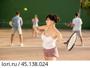 Woman playing frontenis with partners at sunny day, healthy lifestyle concept. Стоковое фото, фотограф Яков Филимонов / Фотобанк Лори