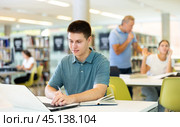 Young male student studying with a laptop in the library. Стоковое фото, фотограф Яков Филимонов / Фотобанк Лори