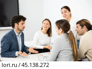 Emotional language teacher telling interesting stories to adult attentive students during class break in auditory. Стоковое фото, фотограф Яков Филимонов / Фотобанк Лори