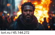 A close-up of a man against a backdrop of mass riots. Behind him, a fire is visible, symbolizing protest, chaos, and tension. The man's gaze is serious and determined, emphasizing his involvement in what is happening. The blurred background with people and flames creates a dramatic atmosphere, enhancing the emotions of the scene. Стоковое AI-изображение, AI-художник Анна Кривицкая / Фотобанк Лори